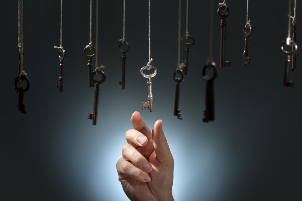 Hand choosing a key out of several hanging ones