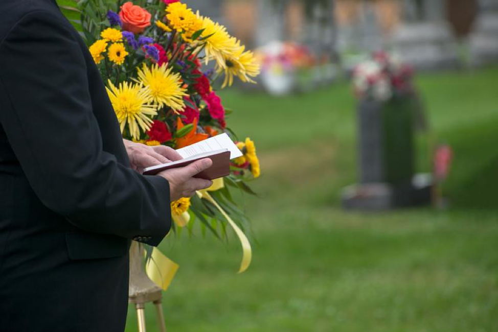 Flowers and pray reading at a funeral.